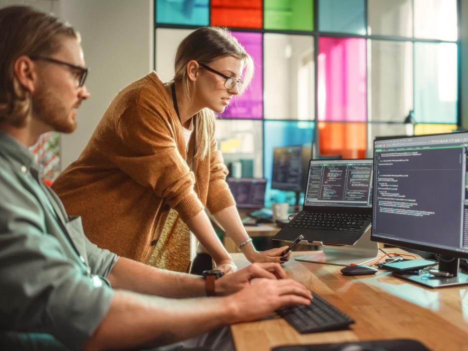 Two developers work collaboratively towards a programming solution for an application in an office.